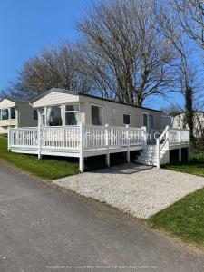 ein Mobilheim mit Veranda und weißem Zaun in der Unterkunft Cosy 2 bed pet friendly holiday home Crantock Nr Newquay in Crantock