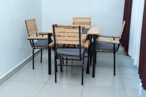 Green V Apartments في كيغالي: طاولة طعام مع أربعة كراسي وطاولة وكرسي