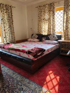 1 dormitorio con 1 cama grande y alfombra roja en Bashaw Residency, Top Rated Family Guest House Near Srinagar Airport, en Srinagar