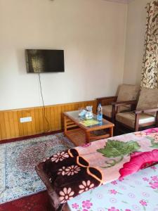 Habitación con cama, mesa y TV. en Bashaw Residency, Top Rated Family Guest House Near Srinagar Airport, en Srinagar