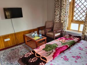 a room with a bed and a table and a tv at Bashaw Residency, Top Rated Family Guest House Near Srinagar Airport in Srinagar