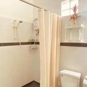 a bathroom with a shower curtain and a toilet at Abihon HoferHaus Mactan Guesthouse in Lapu Lapu City