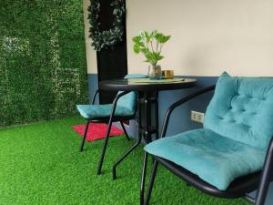a table with two chairs and a table with green carpet at Casita de Reina Staycation House - A cozy 1-Bedroom condo-style house in Locsin