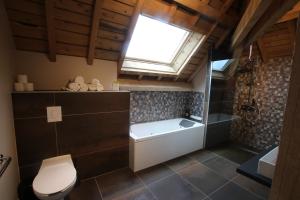 een badkamer met een bad, een toilet en een raam bij Les Loges Du Parc in Gérardmer