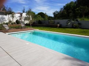 a swimming pool in a yard next to a fence at Les Echappees belles - La Villa in Tarnos