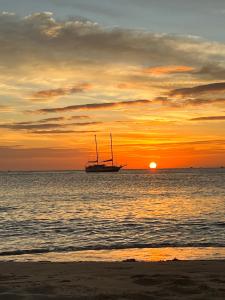 a sail boat in the ocean at sunset at Wave Sound Beach House Phu Quoc in Phu Quoc