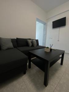 een woonkamer met een zwarte bank en een salontafel bij Uka apartment in Nea Iraklia