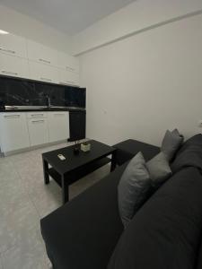 een woonkamer met een zwarte bank en een tafel bij Uka apartment in Nea Iraklia