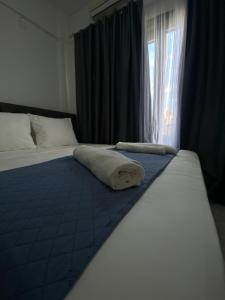 a bedroom with a bed with a blue blanket and a window at Uka apartment in Nea Iraklia