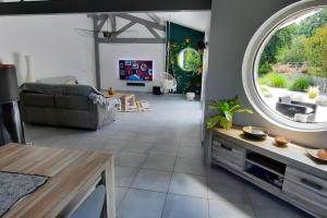 uma sala de estar com um sofá e uma grande janela em Villa piscine chauffée dans un écrin de verdure em Biscarrosse