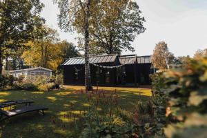 einen Garten mit einer Bank und einem schwarzen Gebäude in der Unterkunft Fika Tiny House in Epe
