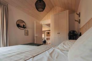 a bedroom with a white bed and a wooden ceiling at Fika Tiny House in Epe