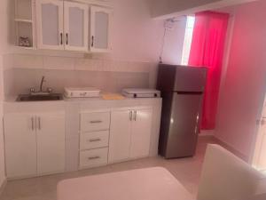 a kitchen with white cabinets and a black refrigerator at Residencial Lucy in Boca Chica