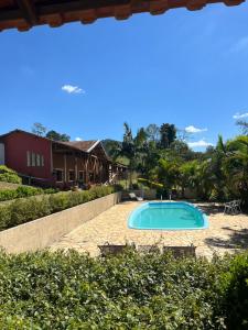 a swimming pool in a yard next to a house at Pousada Pedra da Mina in Passa Quatro