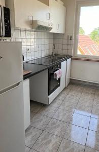 eine Küche mit weißen Geräten und einem großen Fenster in der Unterkunft Appartement spacieux Schilk in Straßburg