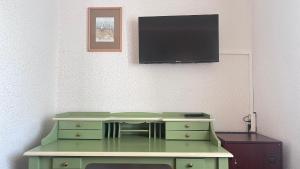 een groene dressoir met een flatscreen-tv aan de muur bij LandhotelUllrich in Baumholder