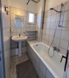 ein Badezimmer mit einer Badewanne und einem Waschbecken in der Unterkunft Appartement spacieux Schilk in Straßburg