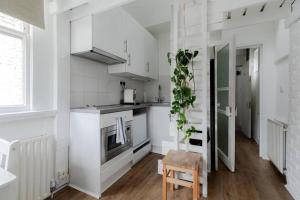 a kitchen with white cabinets and a table and a chair at Charming Primrose Hill Loft near train station in London