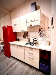 eine Küche mit weißen Schränken und einem roten Kühlschrank in der Unterkunft Апартаменти Smereka in Jablunyzja