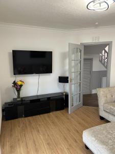 uma sala de estar com uma televisão de ecrã plano na parede em House in Stoneywood Dyce em Aberdeen