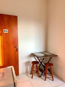 a table and two stools in a room with a door at Pousada Aconchego De São Thomé in São Thomé das Letras