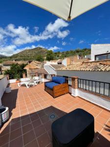 un patio con sillas y una sombrilla en el techo en Casa Morayma, Lecrin, Granada (Adult Only Small Guesthouse) en Acequias