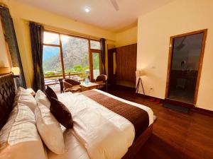 a hotel room with a bed and a large window at Hotel New Panchali With Mountain view By Winterline, Kasol in Kasol