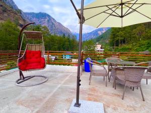 uma cadeira vermelha sentada em cima de uma mesa com um guarda-chuva em Hotel New Panchali With Mountain view By Winterline, Kasol em Kasol