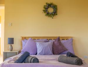 a bed with purple pillows and a wreath on the wall at Pierocks Highgate Entire house Free Parking and WI-FI in Arnos Vale