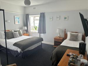Habitación de hotel con 2 camas y mesa en The Yacht Inn en Penzance