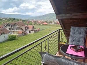 een balkon met een tafel en uitzicht op een veld bij Šumska Vila in Bajina Bašta