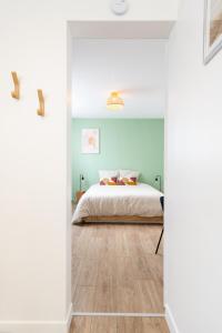 Schlafzimmer mit einem Kingsize-Bett und Holzboden in der Unterkunft Le Noyer - appartement moderne & accessible in Montaigu-Vendée