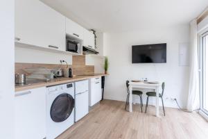 eine Küche mit einer Waschmaschine und einem Tisch in der Unterkunft Le Noyer - appartement moderne & accessible in Montaigu-Vendée