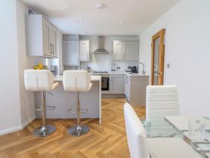a kitchen with white cabinets and a glass table and chairs at 1 Ty Newydd in Porthmadog