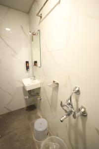 La salle de bains blanche est pourvue d'un lavabo et de toilettes. dans l'établissement Hotel Parashar Palm, à Nagpur