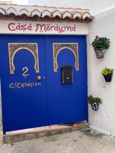 Una puerta azul en un edificio con un cartel. en Casa Morayma, Lecrin, Granada (Adult Only Small Guesthouse) en Acequias