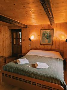 a bed in a wooden room with two towels at La Casa del Busso in Boccioleto