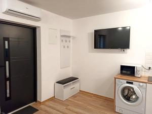 uma lavandaria com uma máquina de lavar roupa e uma televisão em Apartamenty 4You 3 em Zator