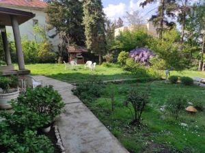 a garden with two white chairs in the grass at Apartman Pobednik in Belgrade