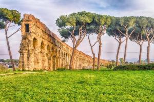 un vieux mur en pierre avec des arbres dans un champ dans l'établissement Rifugio degli Acquedotti Romani, à Rome