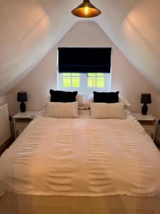 um quarto com uma grande cama branca e uma janela em The Little Thatch - Close to Marlow and Henley em Marlow