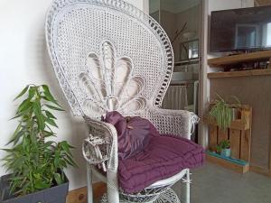 une chaise blanche en osier avec un siège pourpre dans l'établissement Appartement Centre ville Terrasse, à Tarbes