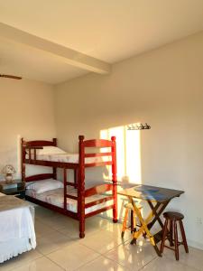 a room with two bunk beds and a table at Pousada Aconchego De São Thomé in São Thomé das Letras