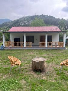 una casa con un tronco de árbol delante de ella en C O Z Y Hut At Country Club Balakot en Bālākot