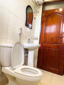 een badkamer met een toilet en een houten deur bij Sweet home apartment in Namulanda