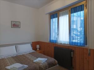 1 dormitorio con 1 cama y ventanas con cortinas azules en Affitta camere Via Piave, en Foligno