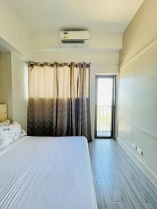 a bedroom with a white bed and a window at WV 8 Serene Family Room in Iloilo City