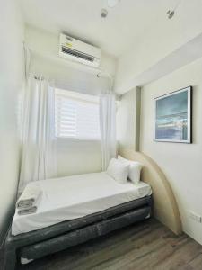 a white room with a bed with a window at WV 8 Serene Family Room in Iloilo City