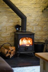 a stove with a fire in a room at NEW Toad Hall Lake Access & Pet Friendly in Somerford Keynes
