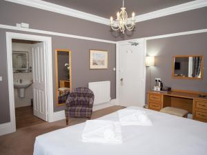 a bedroom with a bed and a desk and a chair at Lyzzick Hall Hotel in Keswick